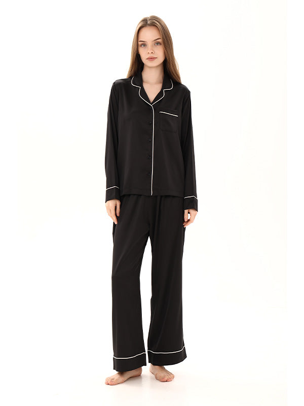 Woman wearing black pajamas with white piping on a white background