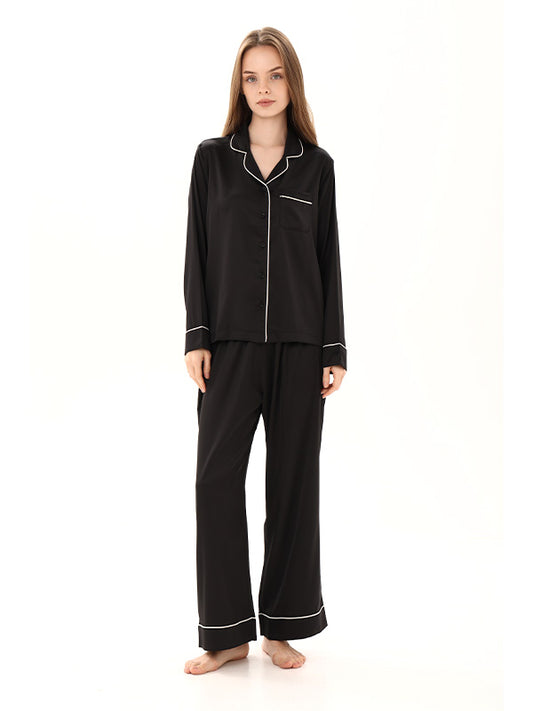 Woman wearing black pajamas with white piping on a white background